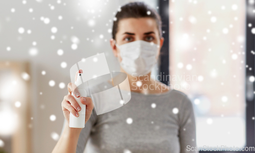 Image of close up of woman in mask holding hand sanitizer