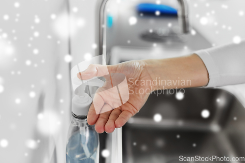 Image of woman washing hands with liquid soap in kitchen