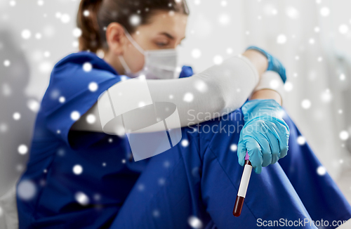 Image of sad doctor or nurse holding beaker with blood test