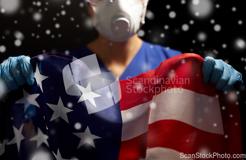 Image of doctor in goggles and mask holding flag of america