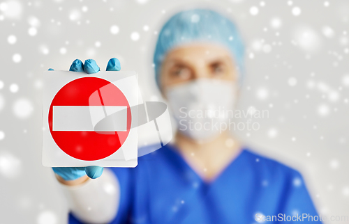 Image of doctor or nurse in face mask showing stop sign