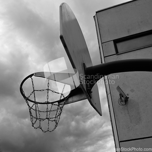 Image of an anti-vandal basketball hoop with iron chains against a gloomy