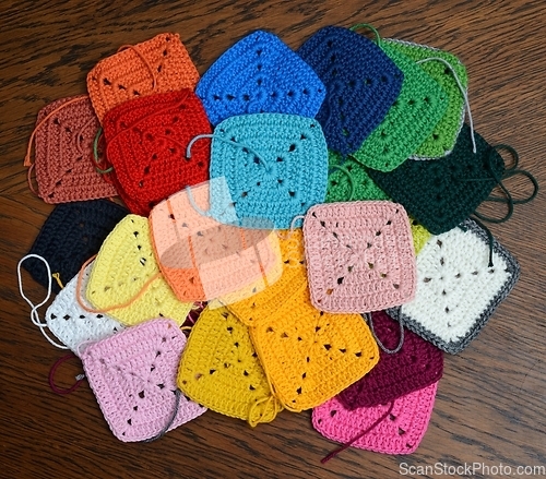 Image of colorful knitted squares on the wooden background