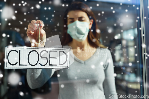 Image of woman in mask hanging banner closed on door