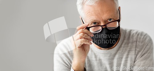 Image of close up of senior man in glasses and black mask