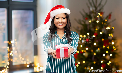 Image of happy asian woman with christmas gift at home