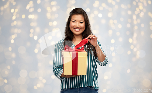 Image of happy asian woman opening gift box