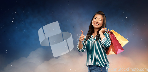 Image of asian woman with shopping bags showing thumbs up