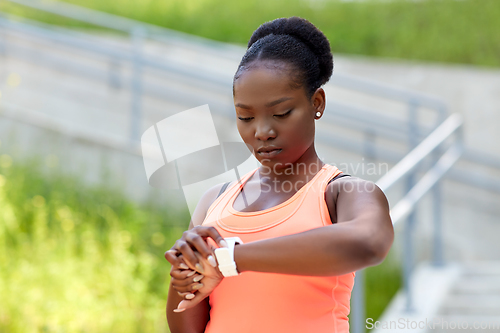 Image of african woman with smart watch doing sports