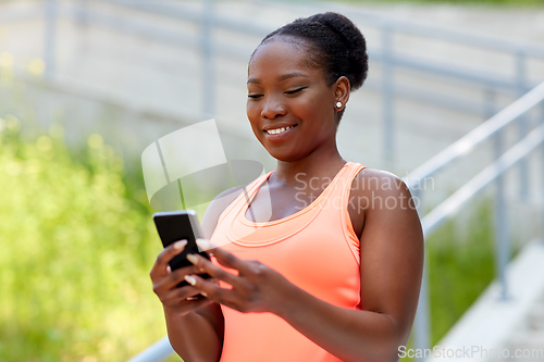 Image of sporty african woman using smartphone in city