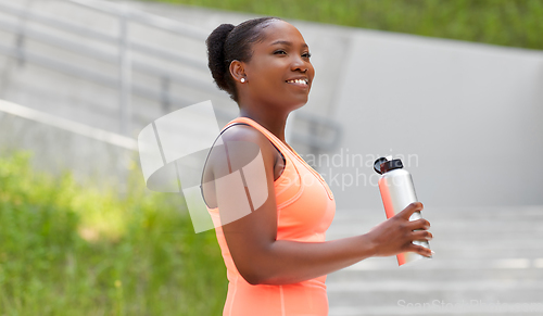 Image of african american woman drinking water from bottle