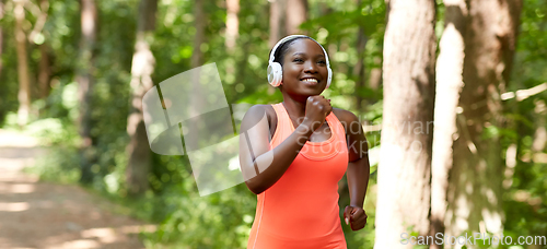 Image of happy african woman in headphones running in park