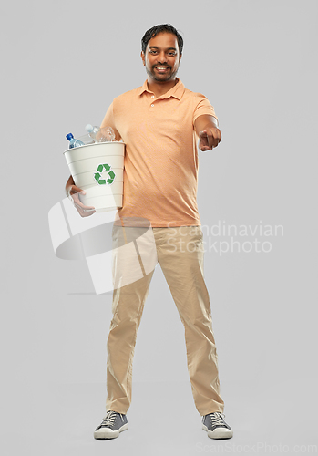Image of smiling young indian man sorting plastic waste
