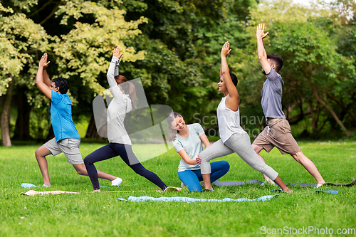 Image of group of people doing yoga at summer park