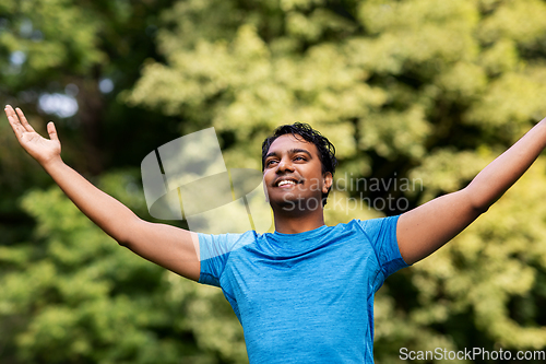 Image of happy indian man doing yoga at summer park