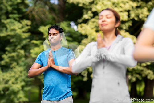 Image of group of people doing yoga at summer park