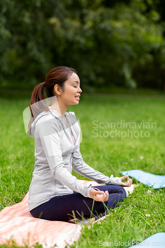 Image of young asian woman meditating at summer park