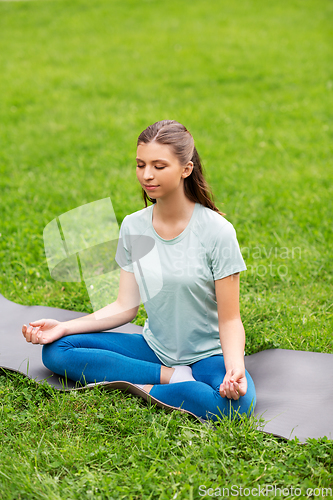 Image of young woman meditating at summer park