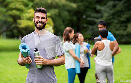 Image of smiling man with yoga mat over group of people