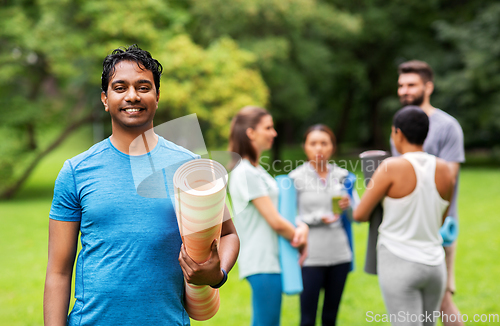 Image of smiling man with yoga mat over group of people