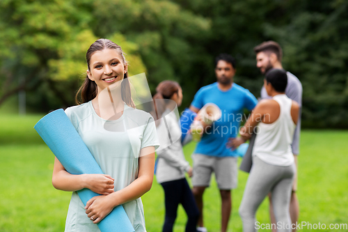 Image of smiling woman with yoga mat over group of people