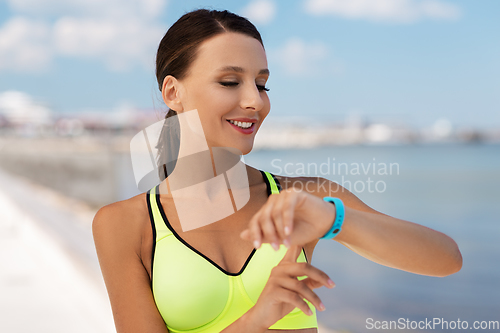 Image of smiling young woman with fitness tracker outdoors