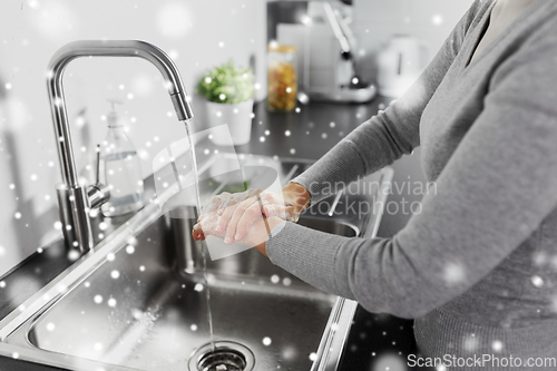 Image of woman washing hands with liquid soap in kitchen