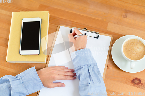 Image of Top view of woman writing on clipboard