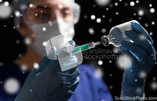 Image of doctor in face mask with syringe and medicine