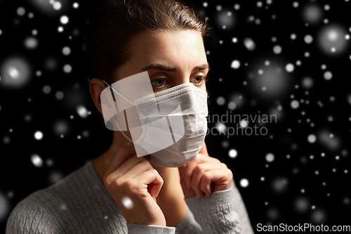 Image of sick woman adjusting protective medical face mask