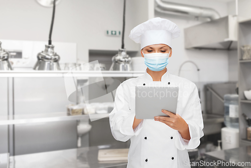 Image of female chef in mask with tablet pc at kitchen