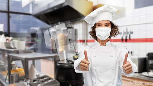 Image of female chef in mask showing thumbs up at kitchen