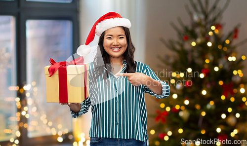 Image of happy asian woman with christmas gift at home