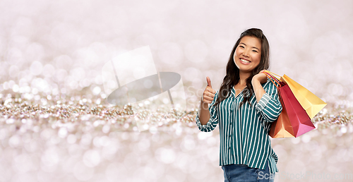 Image of asian woman with shopping bags showing thumbs up