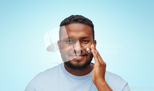 Image of african american man applying moisturizer to face