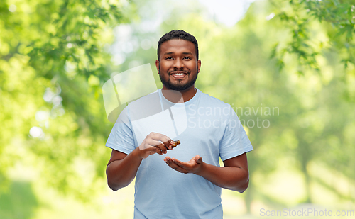 Image of smiling african man applying grooming oil to beard