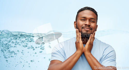 Image of happy african american man touching his beard