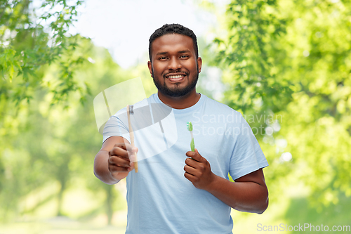 Image of african man with wooden and plastic toothbrushes