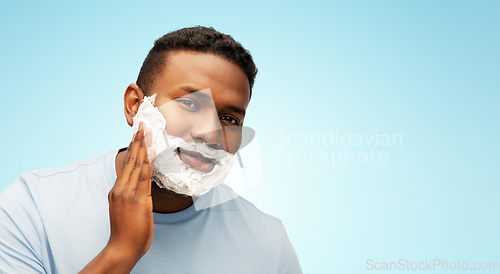 Image of african american man applying shaving foam to face