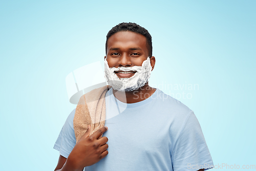 Image of smiling african man with shaving cream and towel