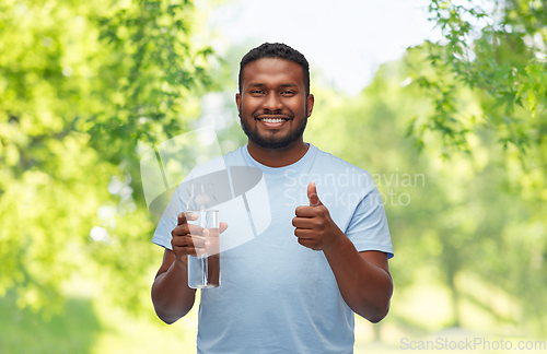 Image of happy african man with water in glass bottle