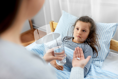 Image of mother giving medicine to sick little daughter