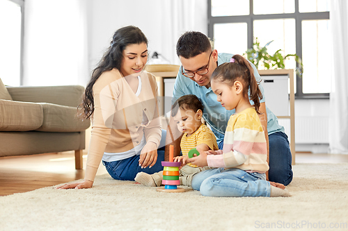 Image of happy family playing with pyramid toy at home