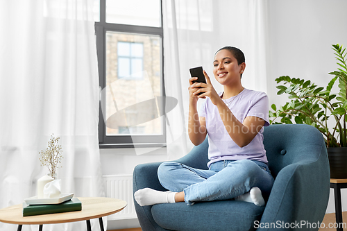 Image of african american woman with smartphone at home