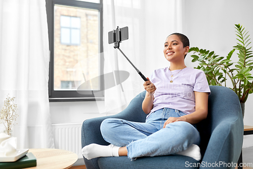 Image of happy african american woman taking selfie at home