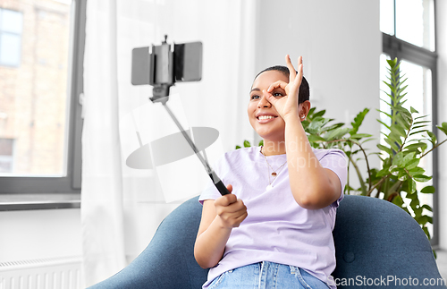 Image of happy african american woman taking selfie at home