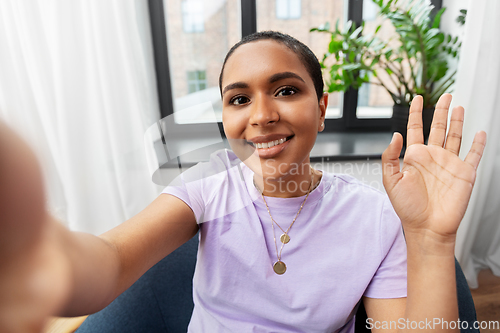 Image of happy african american woman taking selfie at home