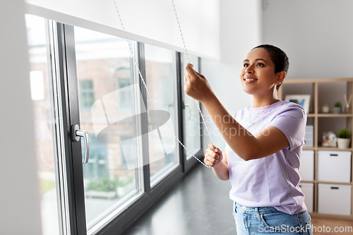 Image of woman opening window roller blinds