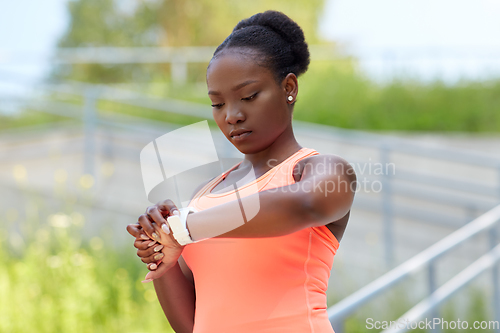 Image of african woman with smart watch doing sports