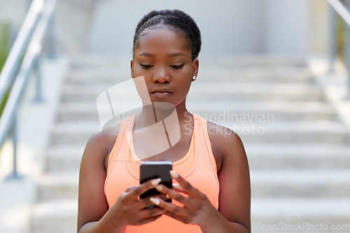 Image of sporty african woman using smartphone in city